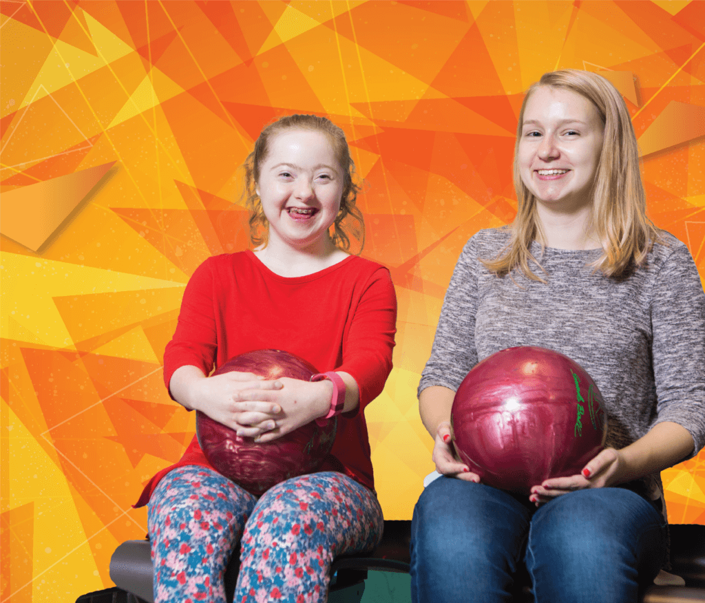 Female mentor and mentee pair smiling and sitting next to eachother with bowling balls