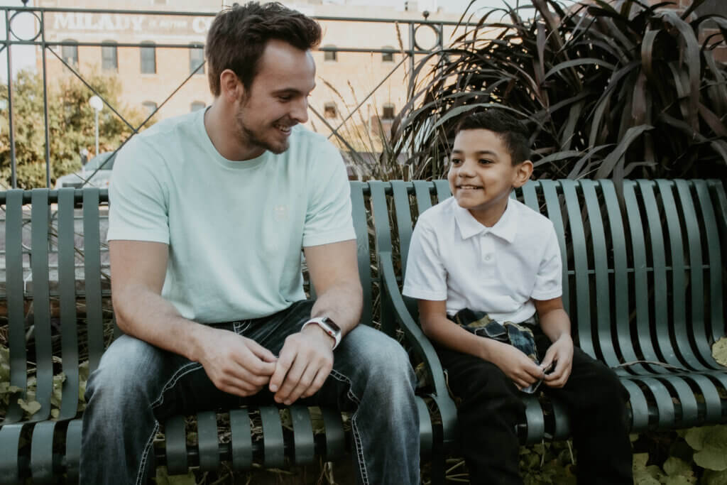 Male mentor and mentee smiling on a bench